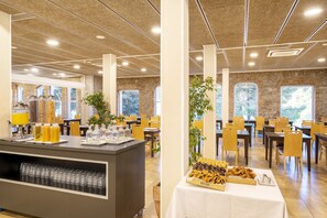 A spacious dining area with high ceilings, large windows, and a buffet setup with various food items and beverages. - Iberik Hotel Balneari Rocallaura (Vallbona de les Monges)