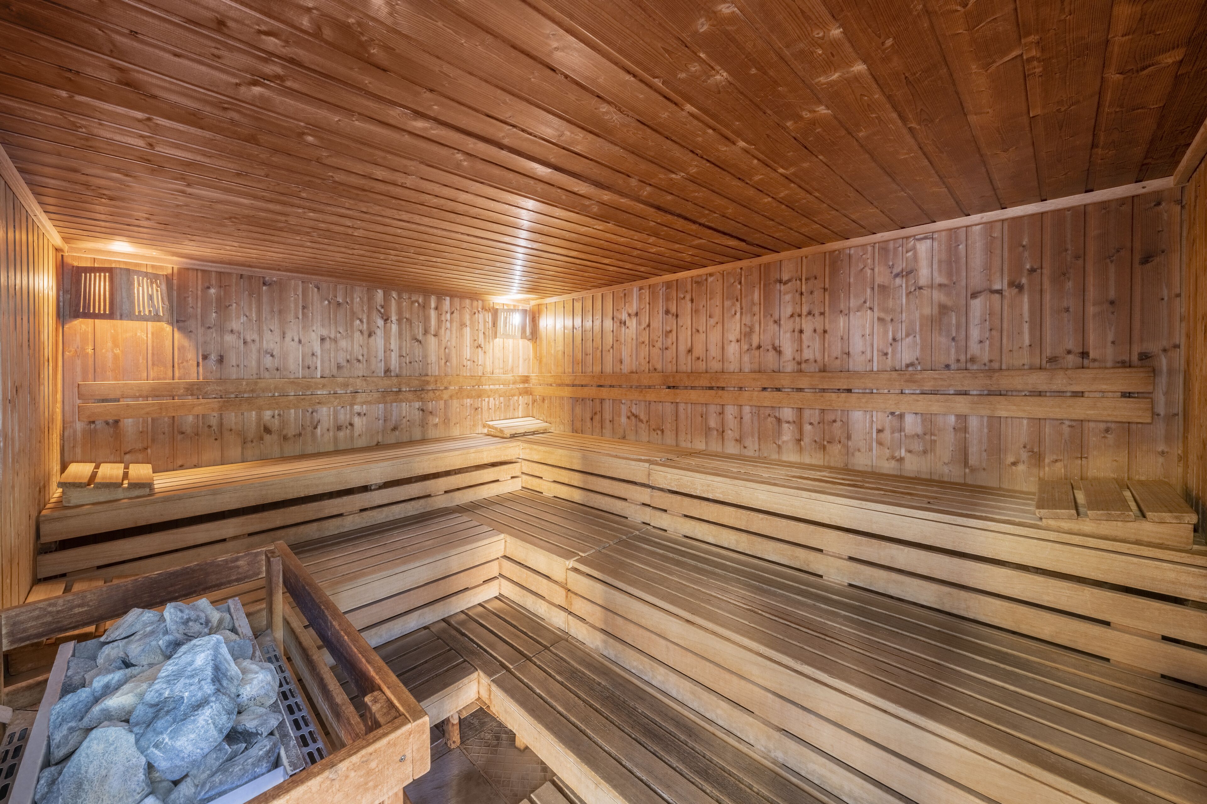 A sauna with wooden benches and a stone basin.