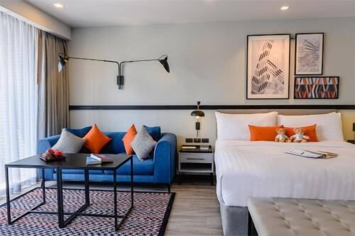 Une chambre d’hôtel avec un lit, un canapé, une table et une lampe.