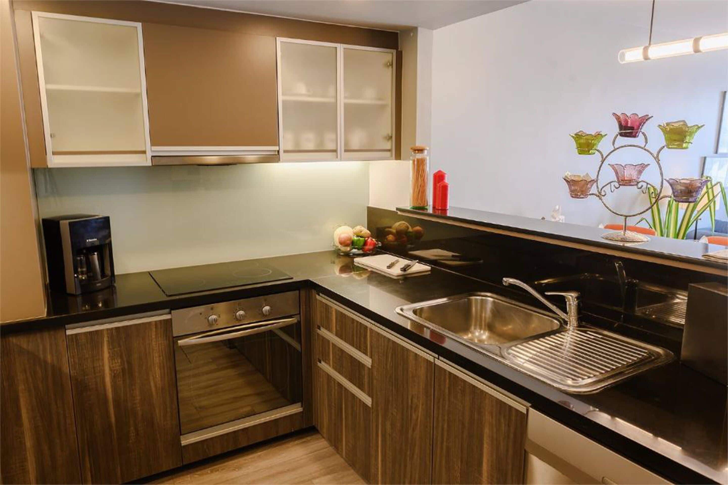Une cuisine moderne avec des meubles en bois, un évier en acier inoxydable et un four encastré.