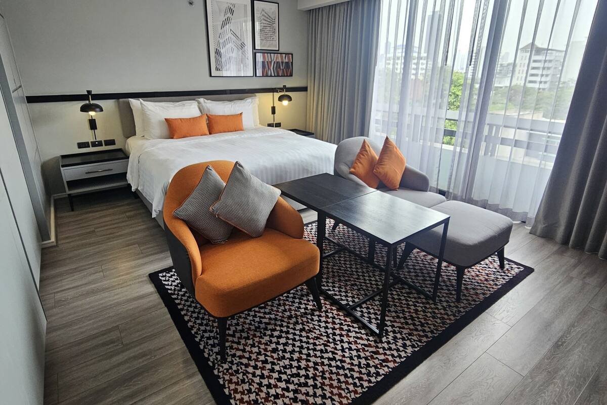 Une chambre d’hôtel moderne équipée d’un lit, d’un canapé, d’une table à manger et d’une grande fenêtre avec des rideaux.