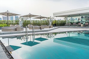 A rooftop pool area with lounge chairs and umbrellas, surrounded by greenery and a cityscape in the background. - Oakwood Residence Sukhumvit Thonglor Bangkok (Bangkok)