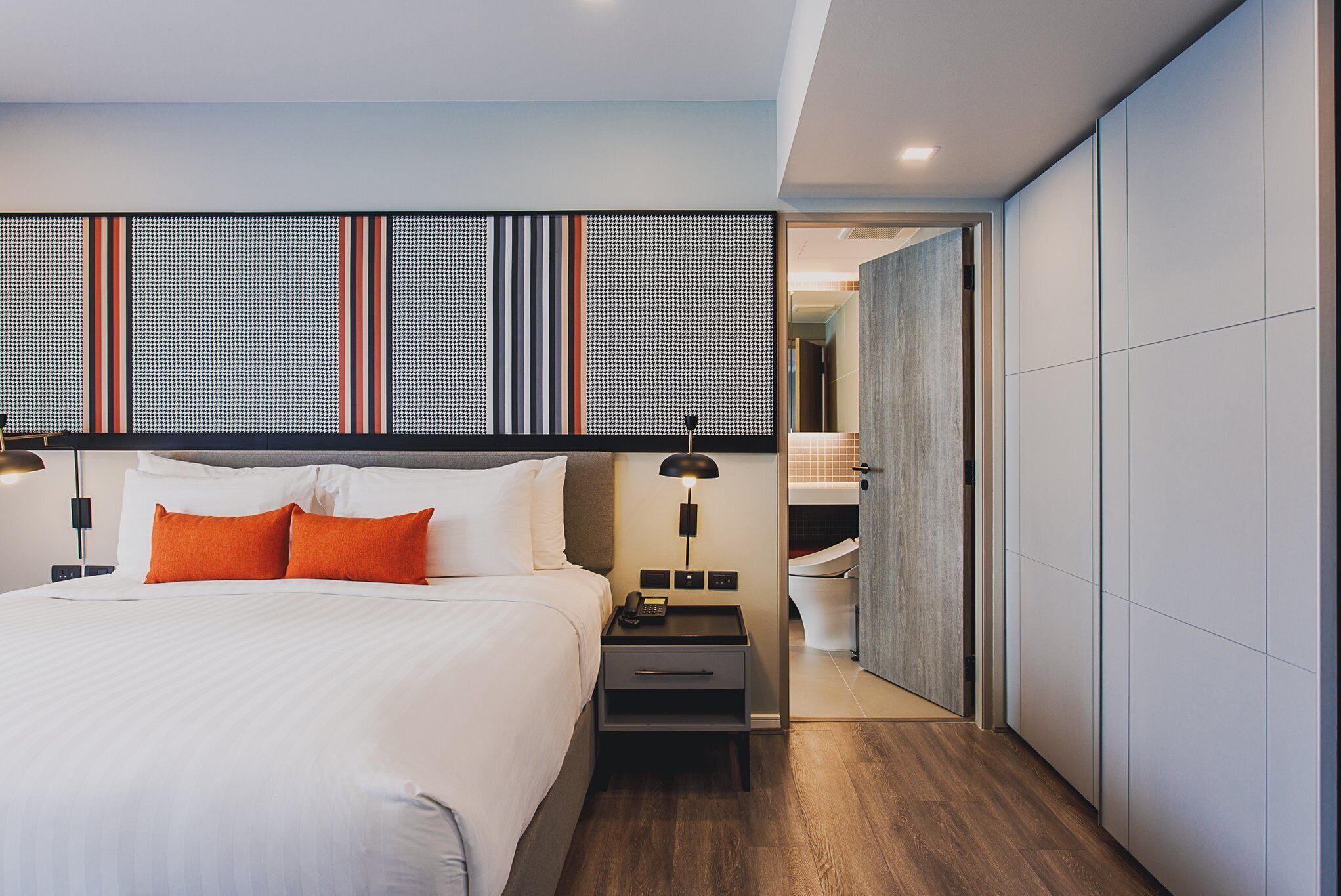 Une chambre d’hôtel moderne avec un grand lit, une table de chevet, une lampe et une vue sur la salle de bain.