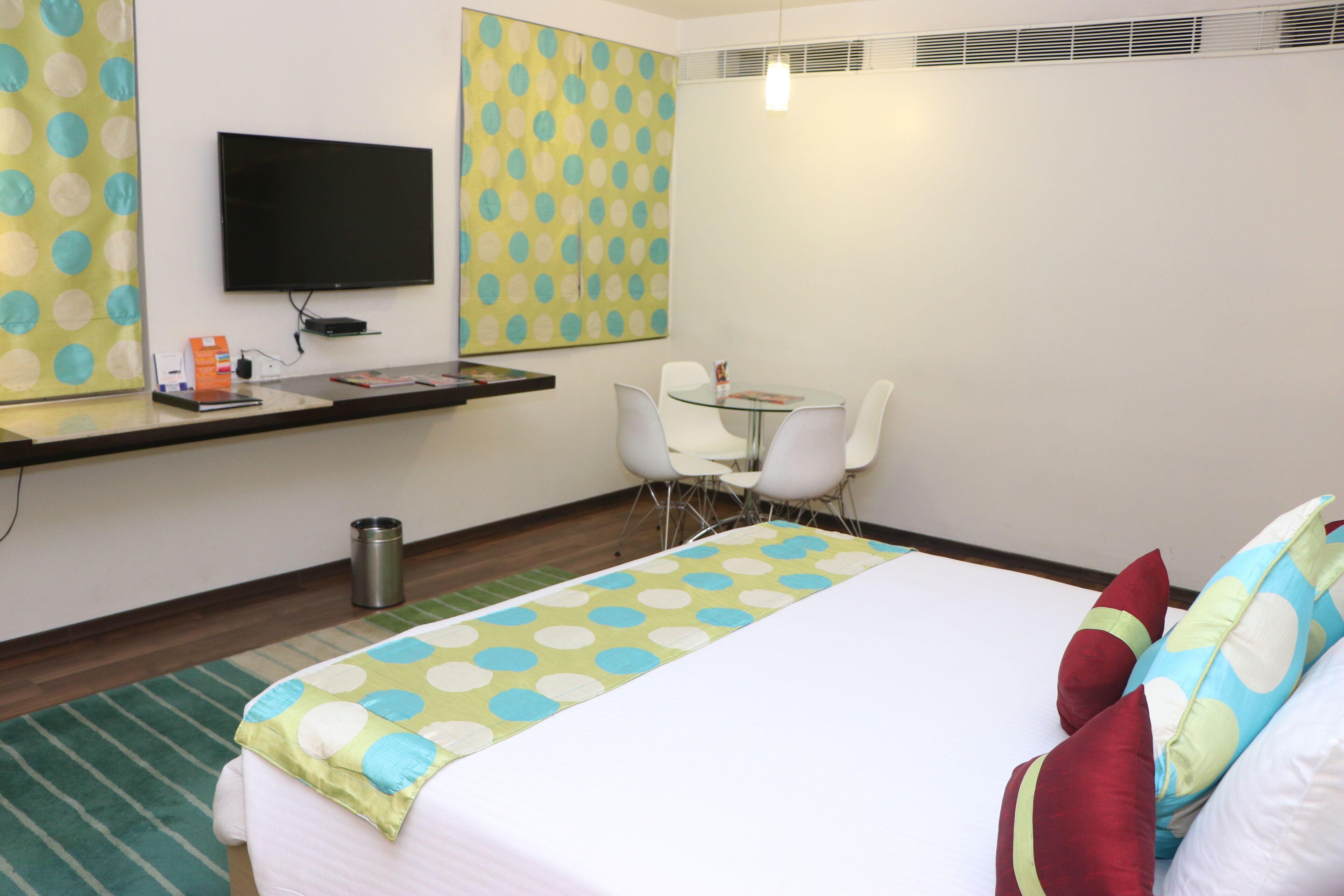 Een hotelkamer met een bed, een bureau, een stoel, een televisie en een behang met patroon.