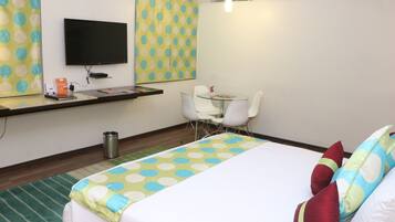 Een hotelkamer met een bed, een bureau, een stoel, een televisie en een behang met patroon.