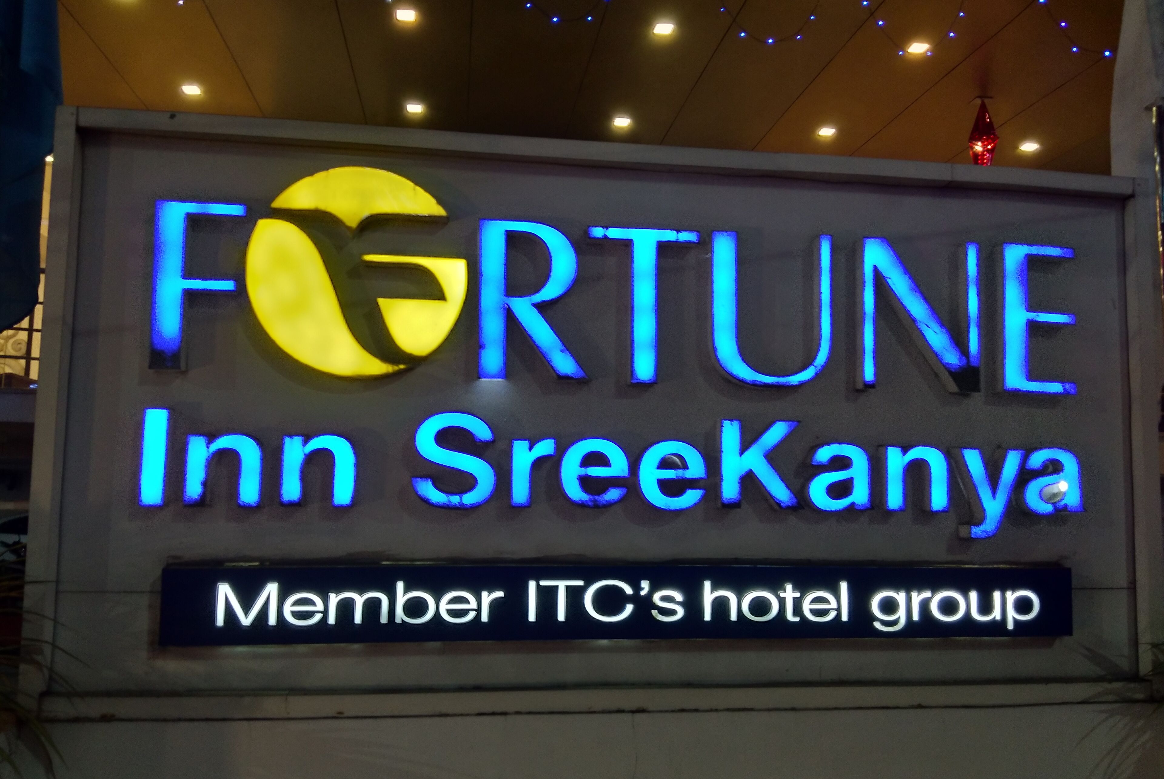 Skilt for Fortune Inn SreeKanya, en del af ITC's hotelgruppe, med oplyste blå og gule bogstaver.