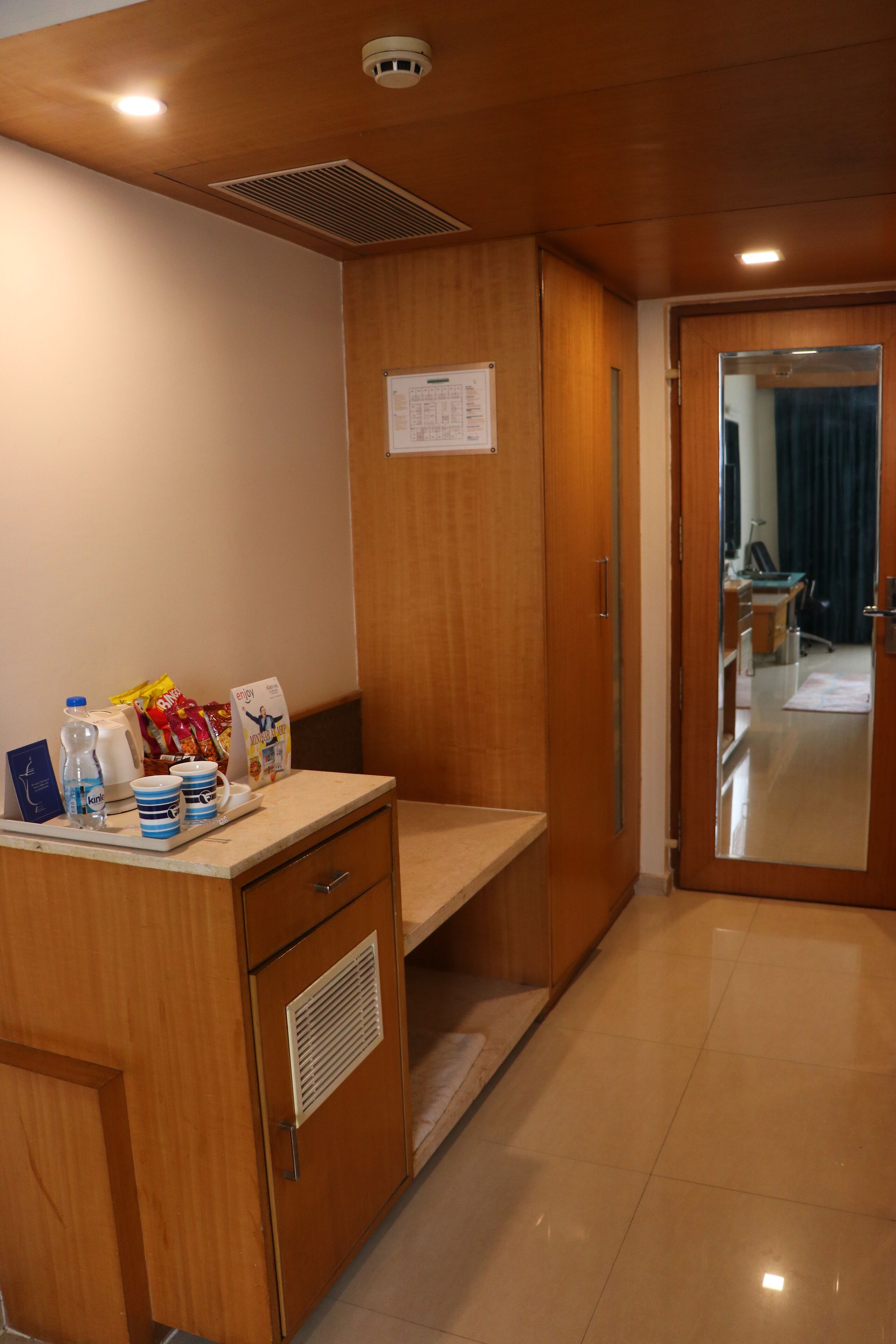 A hotel room with a wooden desk, a mirror, and a door leading to a bathroom.