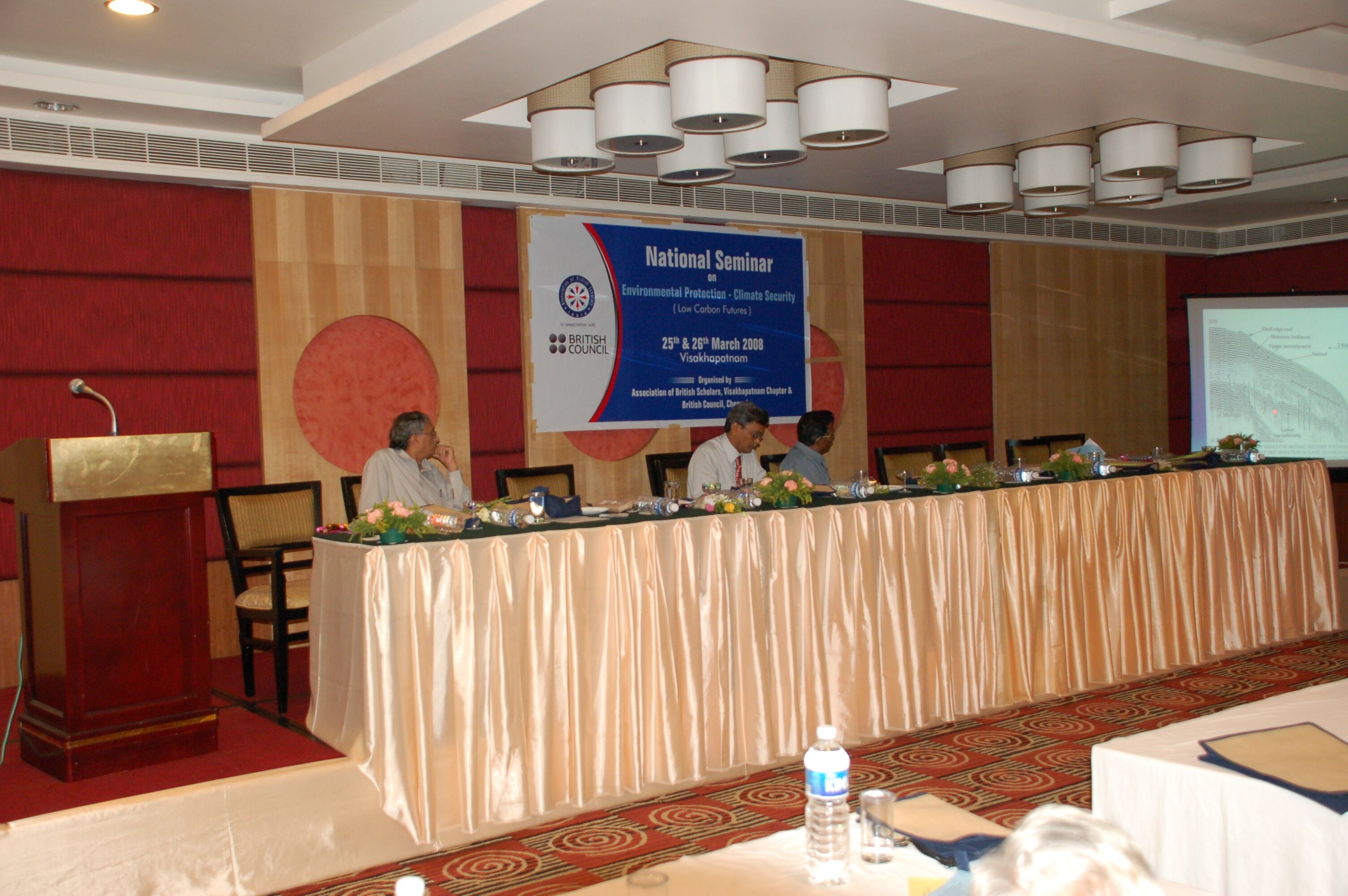A conference room with a long table, a podium, and a banner for a National Seminar on Environmental Protection.