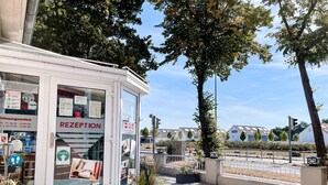 A reception area with a glass door, a sign indicating 'RECEPTION', and a small outdoor seating area with potted plants. - Hotel Falk (Bremen)