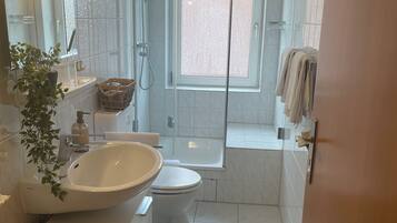 Ein modernes Badezimmer mit großem Waschbecken, Toilette und Duschbereich.