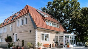 A hotel with a red-tiled roof, a reception area, and potted plants. - Hotel Falk (Bremen)