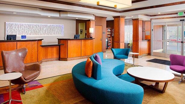 A lobby with a reception desk, a blue sofa, a brown leather chair, and a small table.