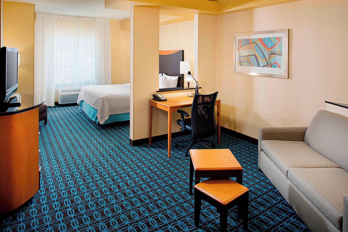 Ein Hotelzimmer mit Bett, Schreibtisch mit Stuhl, einer Sitzecke und einem Fernseher.