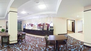 A hotel lobby with a reception desk, seating area, and a patterned floor.