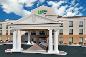 A Holiday Inn Express & Suites with a central entrance, multiple windows, and a clear sky.