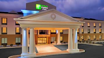 Un Holiday Inn Express & Suites con un padiglione d'ingresso centrale, diversi piani e un'area di parcheggio.