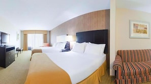 A hotel room with two beds, a TV, a desk, a chair, and a sofa.