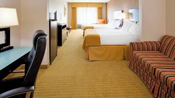 Quarto de hotel com escrivaninha, duas camas, um sofá e uma televisão.