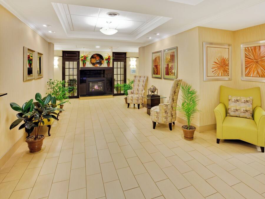 A spacious living room with a fireplace, multiple chairs, potted plants, and artwork on the walls.