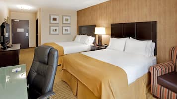 A hotel room with two beds, a desk, a chair, and a television.