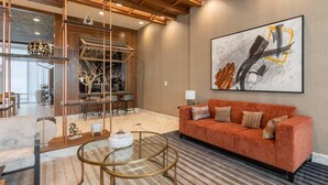A modern living room with a sofa, a glass coffee table, and a bar area with stools. - Delta Hotels by Marriott Raleigh-Durham at Research Triangle Park (Durham)