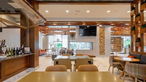 A modern hotel lobby with a wooden reception desk, seating area, and a large TV screen. - Delta Hotels by Marriott Raleigh-Durham at Research Triangle Park (Durham)