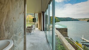 A modern room with a large window overlooking a lake and hills. - Octant Douro (Castelo de Paiva)