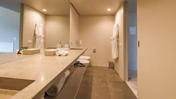 A modern bathroom with a long vanity, two sinks, a toilet, and a trash can.