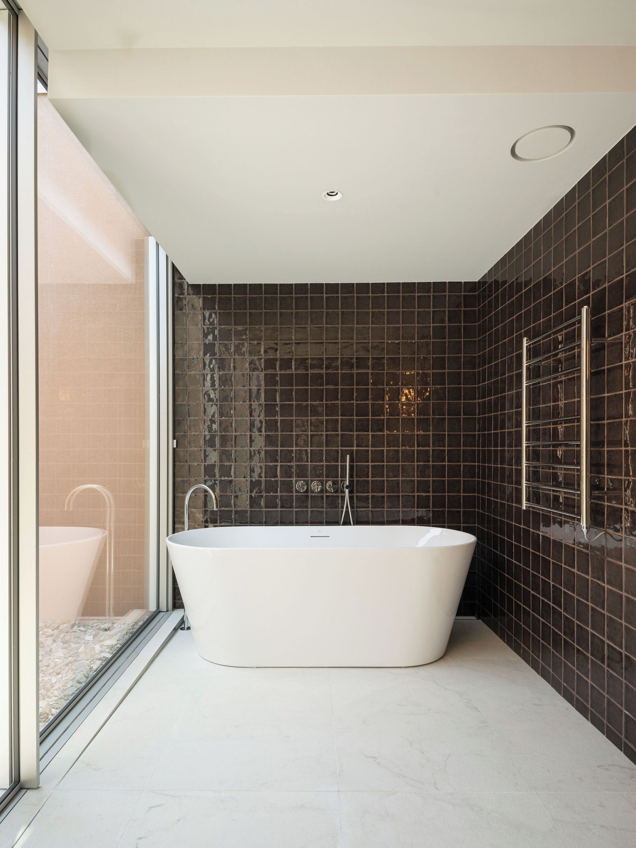 A modern bathroom with a freestanding bathtub, a glass shower enclosure, and a large window providing natural light.