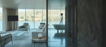 Una sala de estar moderna con un ventanal grande, un televisor de pantalla plana, un sofá y una bañera.