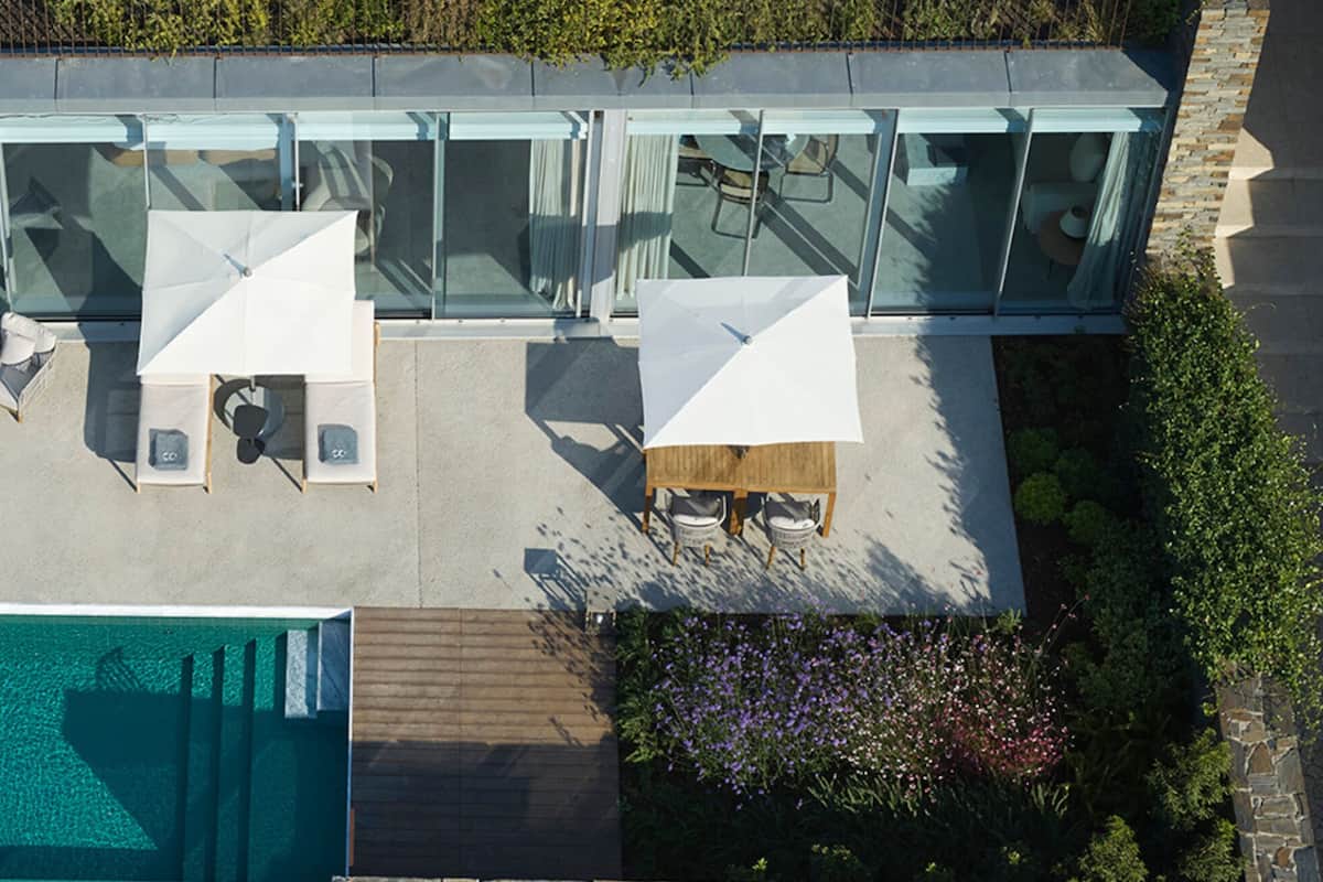 An aerial view of a modern house with a swimming pool, outdoor seating area, and glass doors leading to a patio.