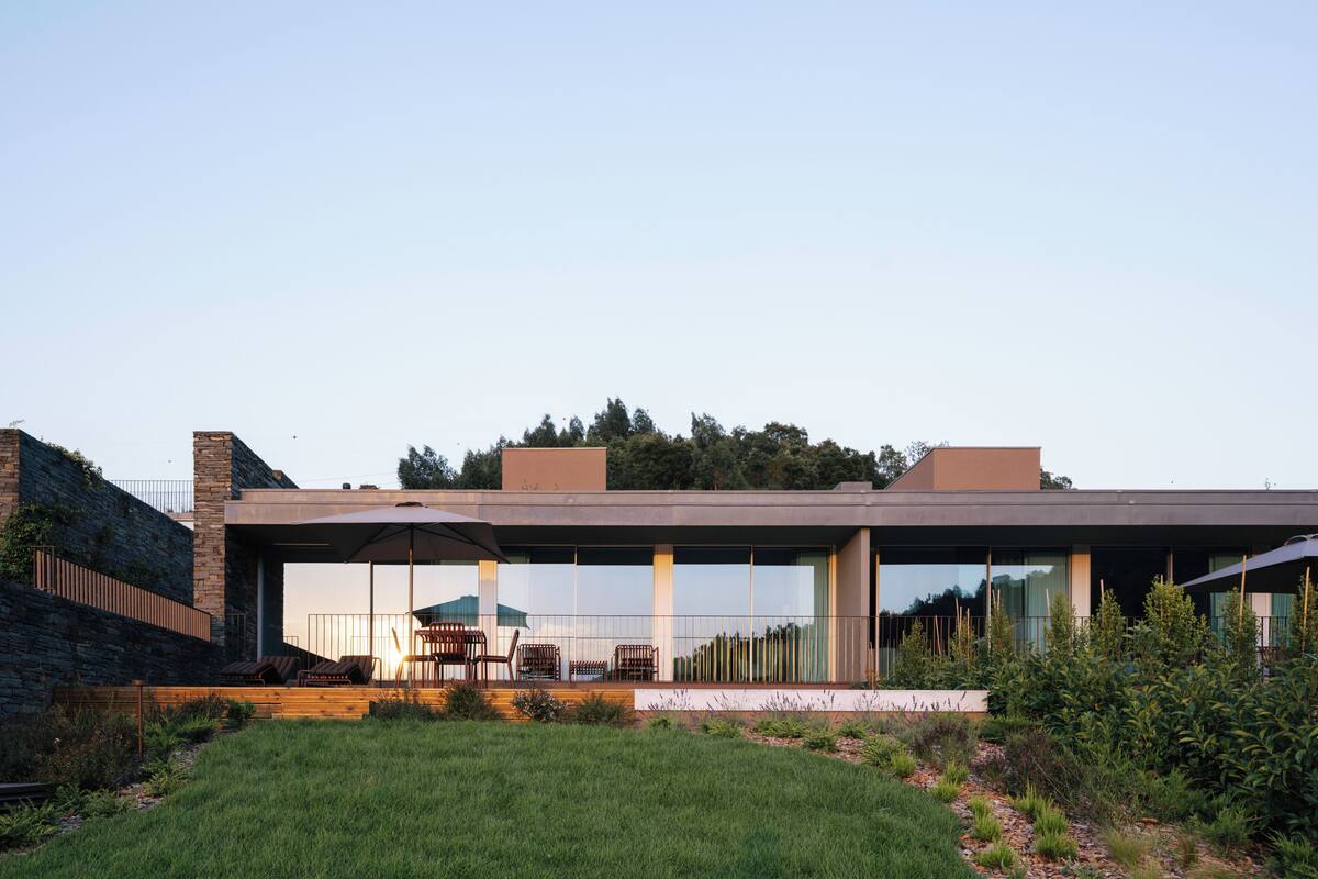 A modern house with a flat roof, large windows, and a patio area with outdoor furniture.