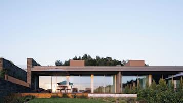 Una casa moderna con techo plano, ventanas amplias y un patio con mobiliario exterior.