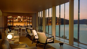 A modern interior with a bar area, seating, and large windows overlooking a body of water. - Octant Douro (Castelo de Paiva)