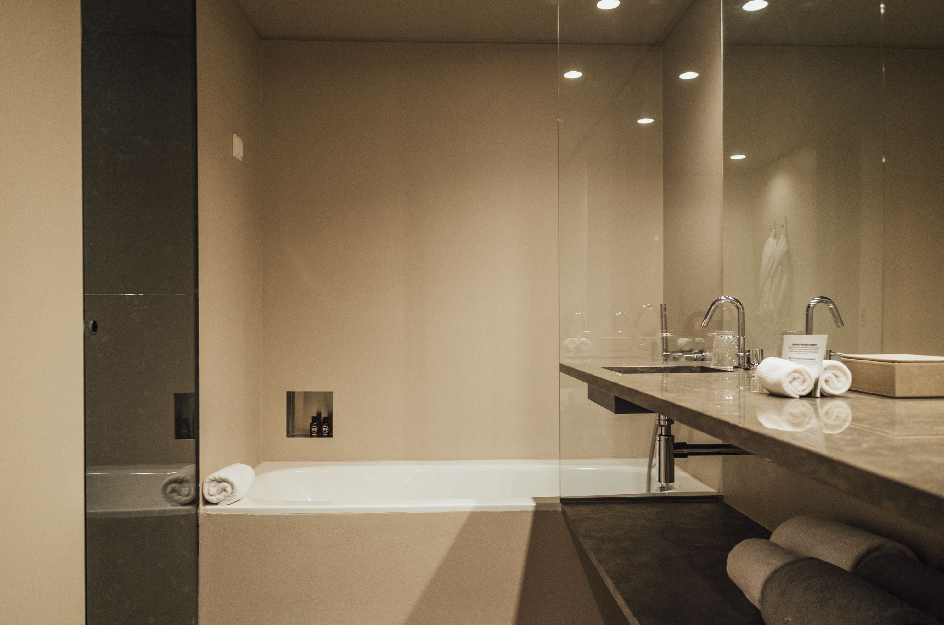 Une salle de bain moderne avec un grand miroir, une baignoire et un meuble-lavabo avec des articles de toilette.