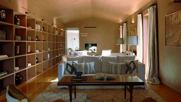 A spacious living room with a large bookshelf, a sofa set, and a coffee table.