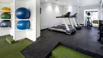 A gym with treadmills, exercise balls, and a green carpeted area.