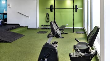 A gym with exercise equipment, a pull-up bar, and a green wall.