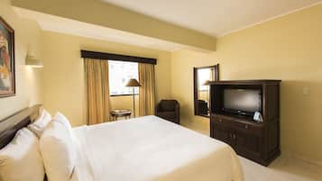 Una habitación de hotel con una cama grande, televisión, una mesita y una silla.