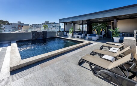 A rooftop pool area with lounge chairs and a waterfall feature.