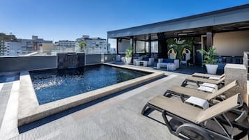 Una piscina al aire libre, sombrillas, tumbonas