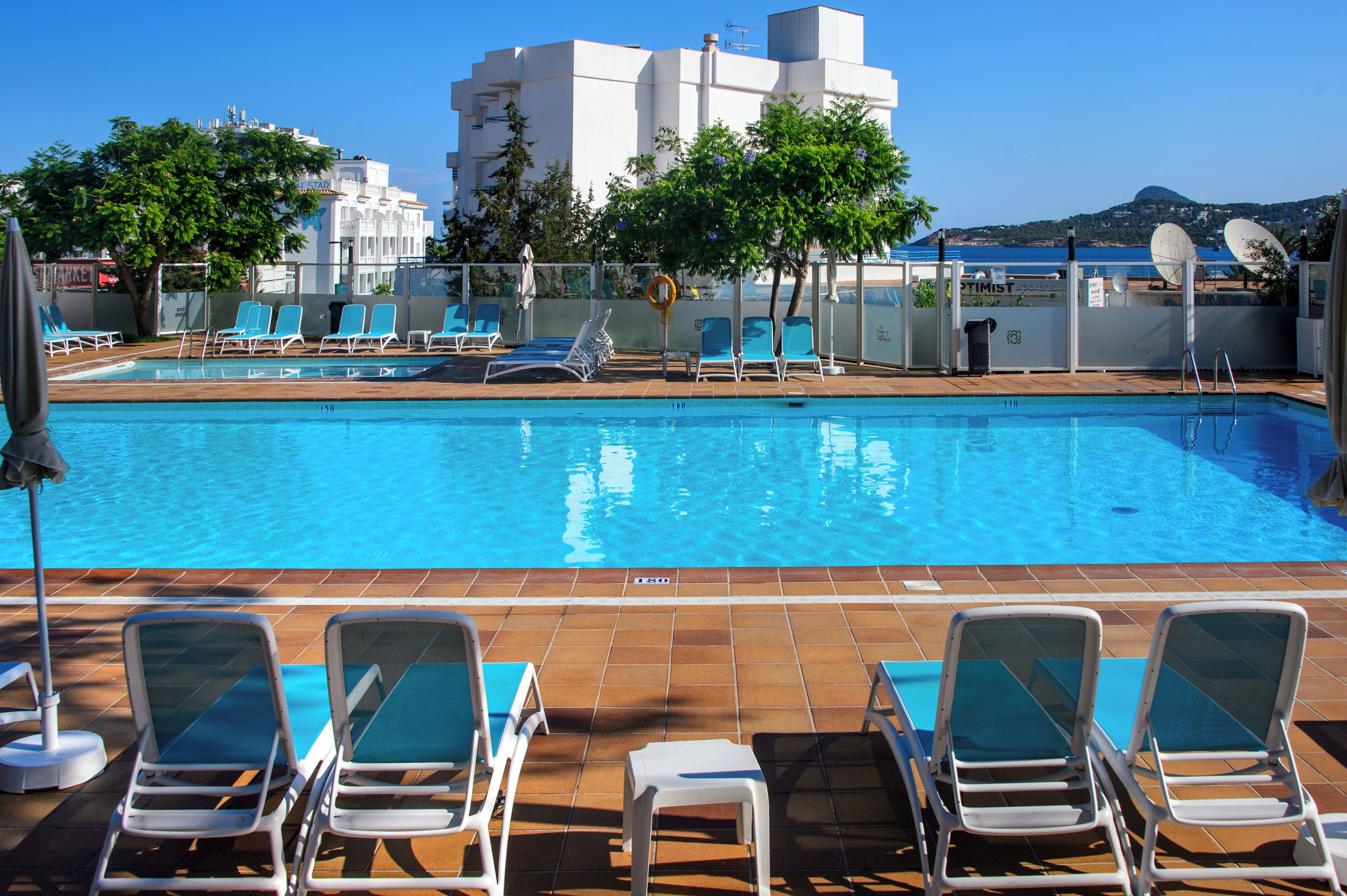 Una piscina con tumbonas y vistas a un paisaje urbano.