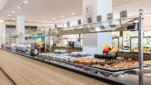 Un bufé con diversos alimentos y un reloj digital que muestra las 12:00.