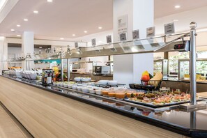 A buffet with various food items and a digital clock displaying 12:00. - Hotel Vibra Riviera (Sant Josep de sa Talaia)