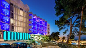 A modern hotel with a unique geometric facade, a visible pool area, and a well-lit entrance. - Hotel Vibra Riviera (Sant Josep de sa Talaia)
