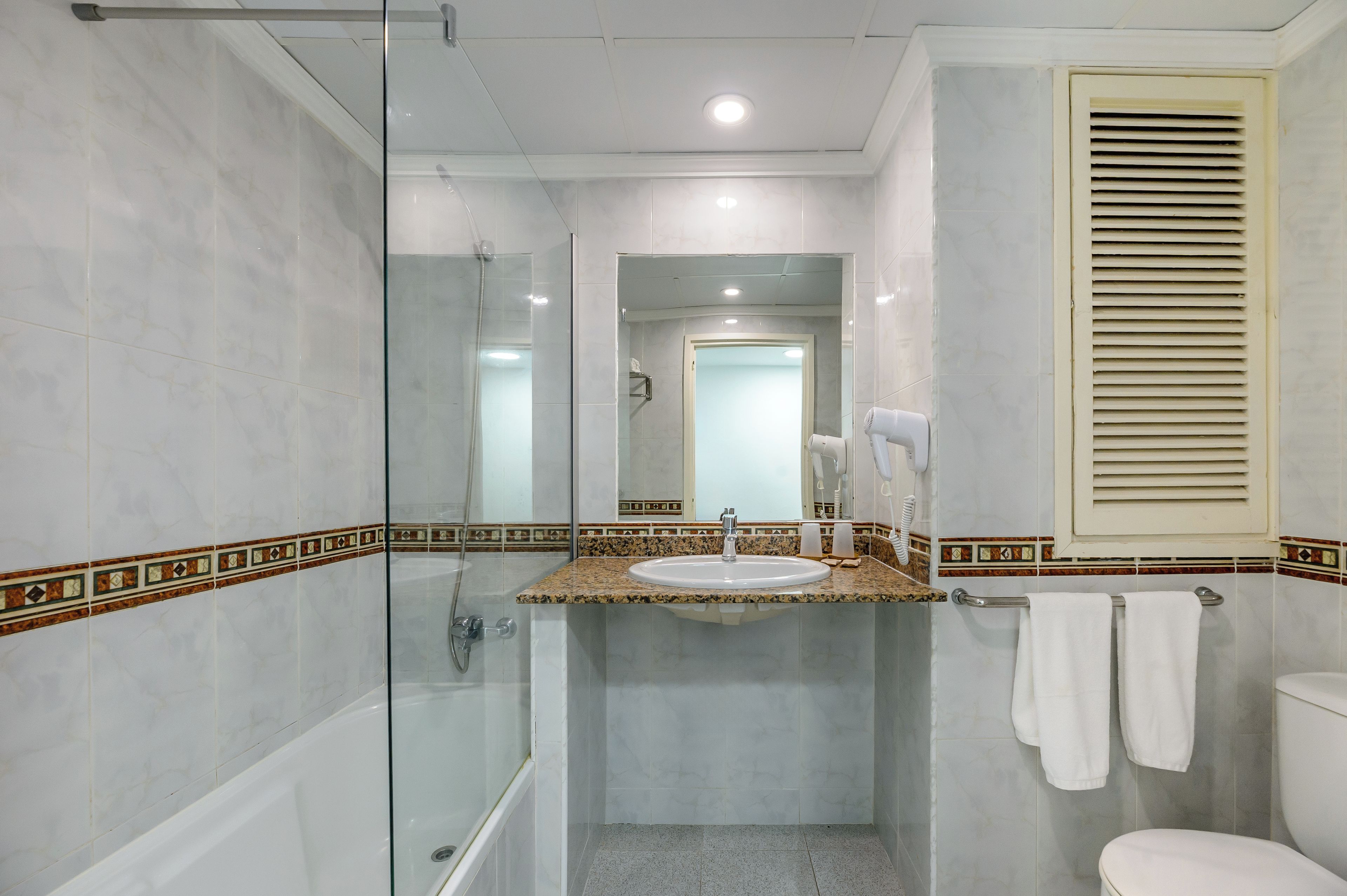 Une salle de bain avec une douche à parois de verre, un lavabo avec un meuble-vasque, des toilettes et un porte-serviettes.