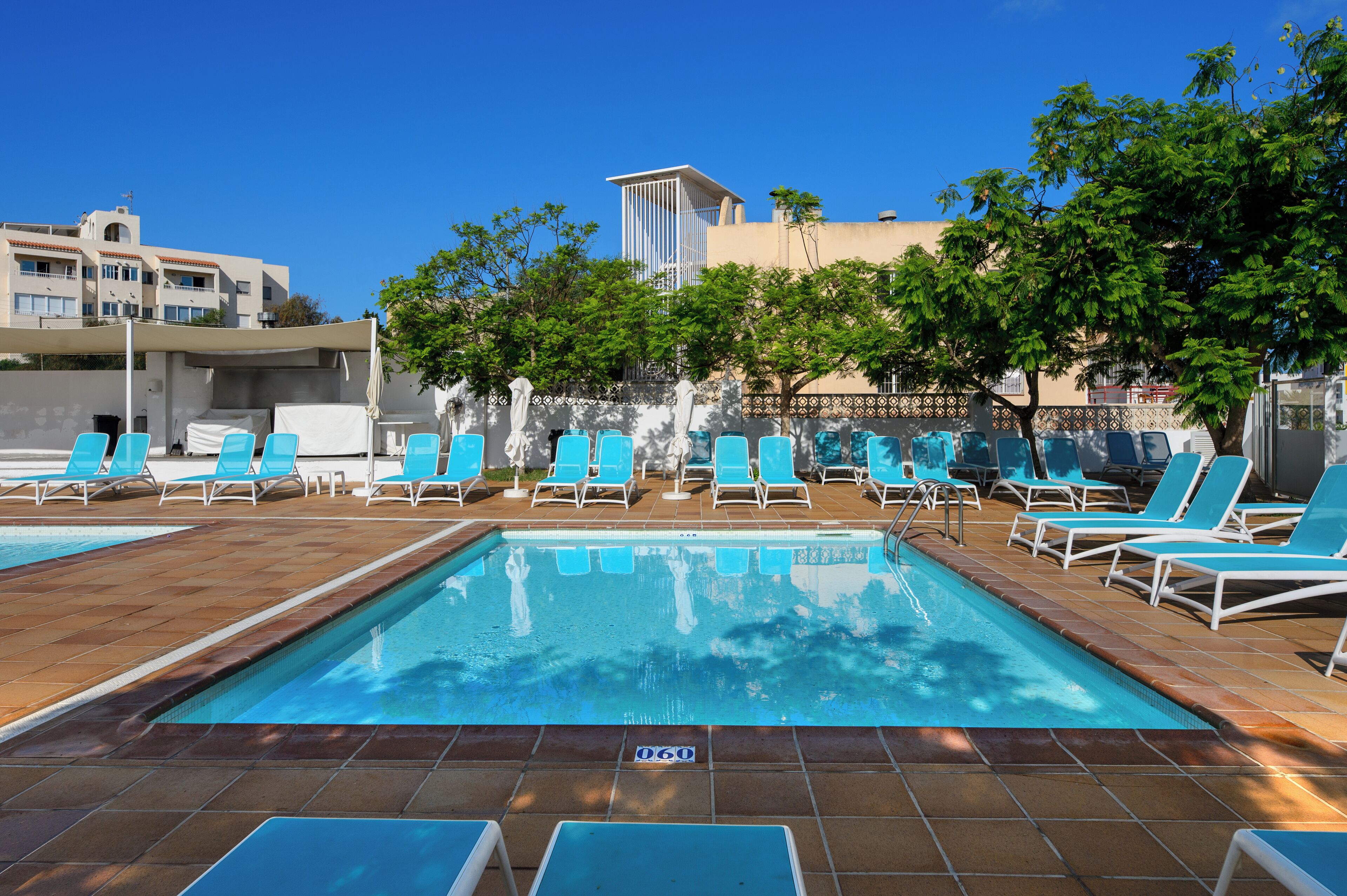 A swimming pool with blue lounge chairs and a tiled deck.