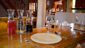 A wooden table set with wine glasses, a plate, and cutlery, with a staircase and wooden interior visible in the background.