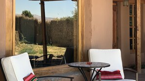 A patio area with two white cushioned chairs and a small round table.