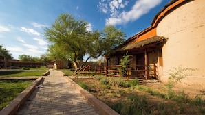 A pathway leading to a traditional building with a thatched roof and wooden structure.